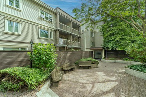 A courtyard surrounded by apartment buildings with a bench and a tree.