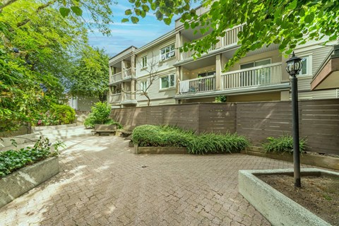 A brick walkway leads to a building with a balcony.