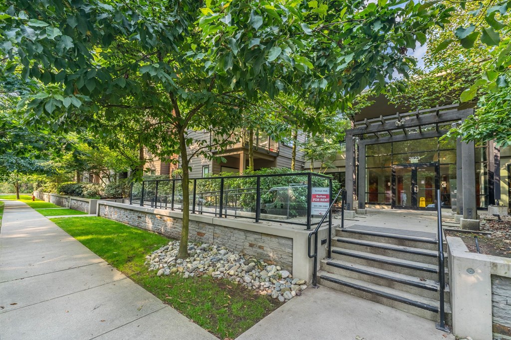 A building entrance with a metal railing and steps leading up to it.