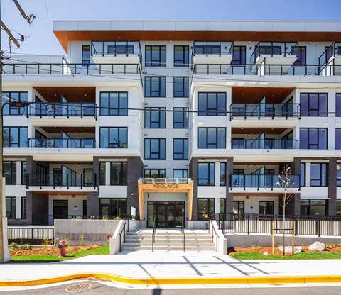 The front of a multi-story apartment building with a fire hydrant in the foreground.