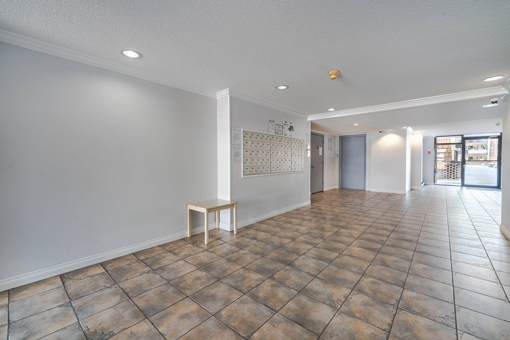 A room with a tiled floor and a white wall with a small table in it.