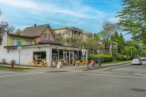 A street view with a building on the left and a car on the road.