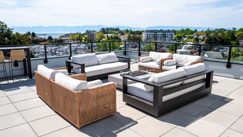 Two white couches on a patio with a view of the water and mountains.