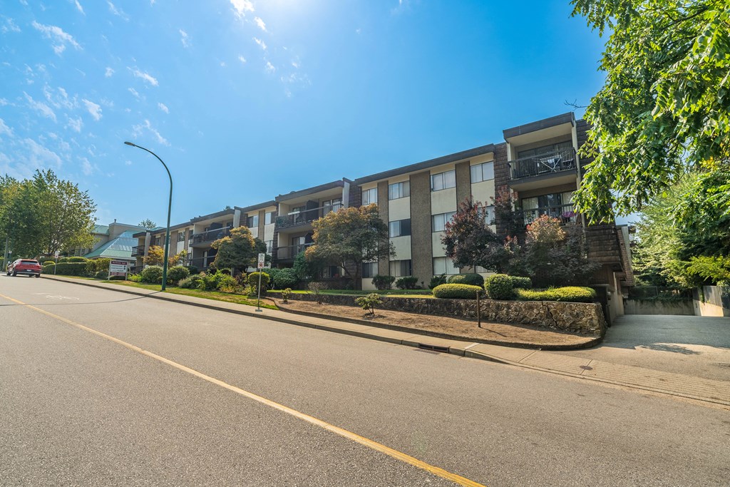 A sunny day on a residential street with apartment buildings on the side.