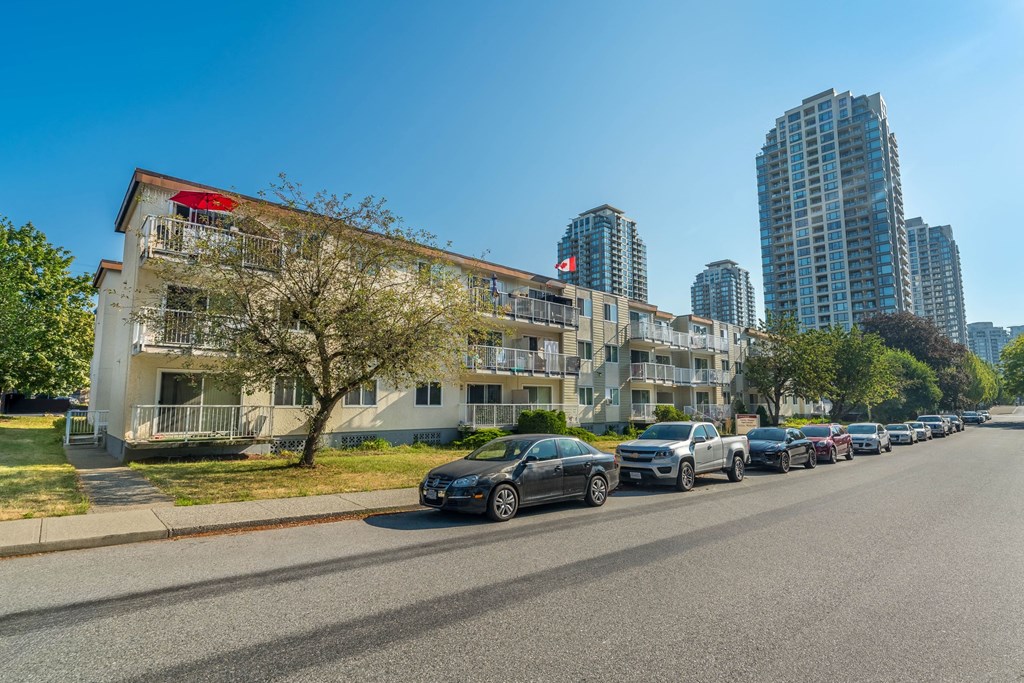 A row of cars parked on the side of a road in front of a building.