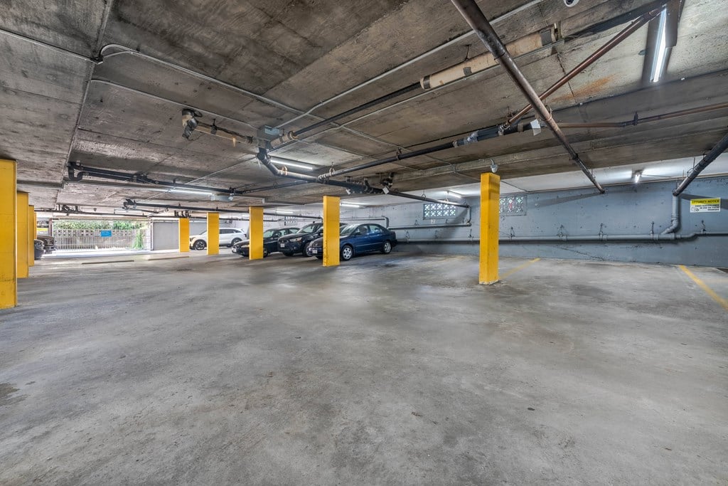 A parking garage with concrete floors and yellow poles.