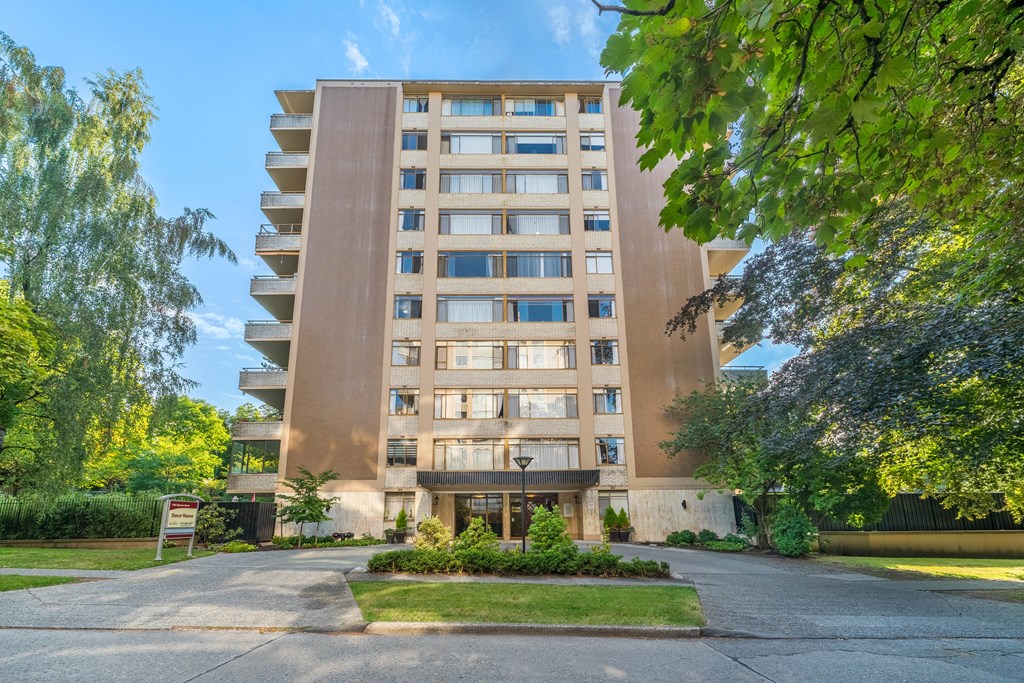 A tall residential building with a green lawn in front.