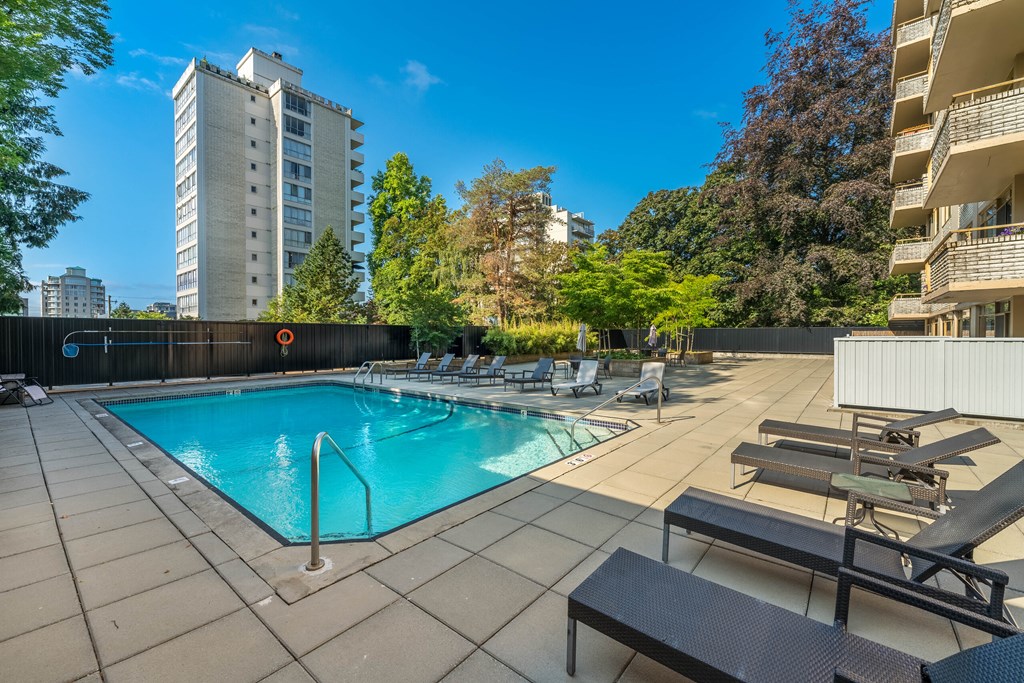 A swimming pool surrounded by lounge chairs and trees.