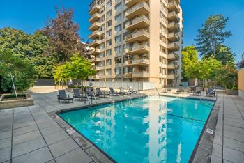 A large swimming pool in front of a tall apartment building.