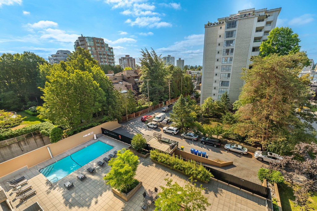 A swimming pool surrounded by trees and a parking lot.