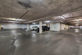 A parking garage with a white car and a black car parked.