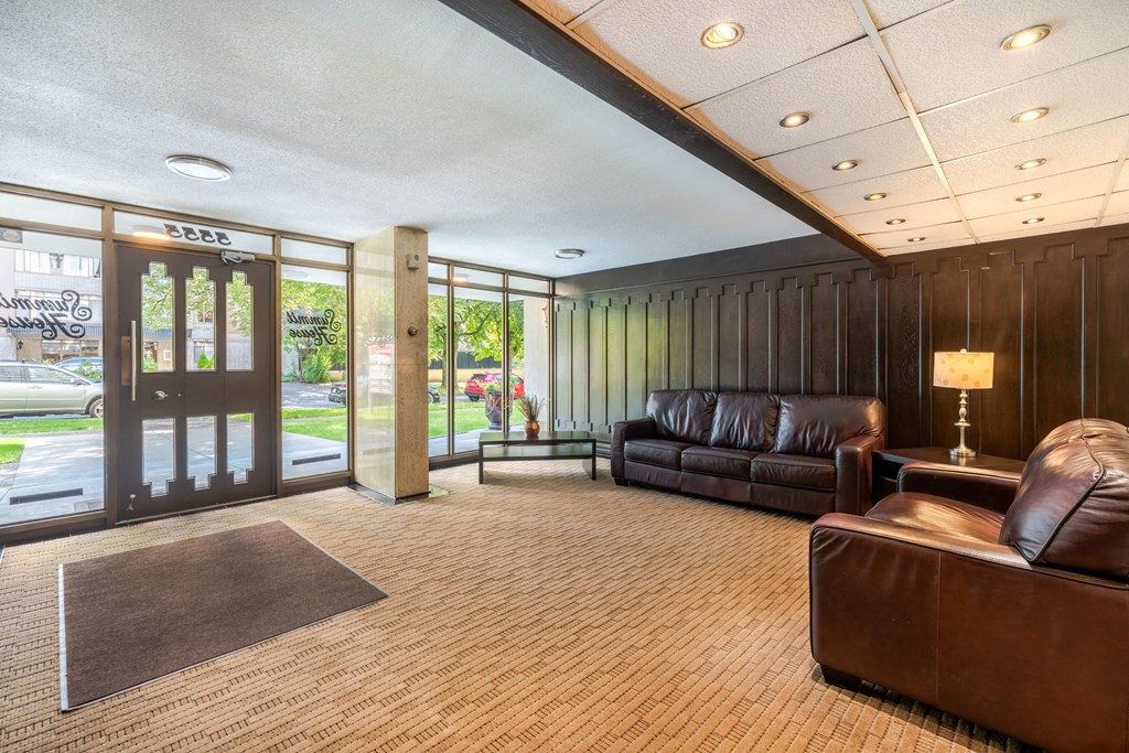 A brown leather couch sits in a room with a brown carpet.