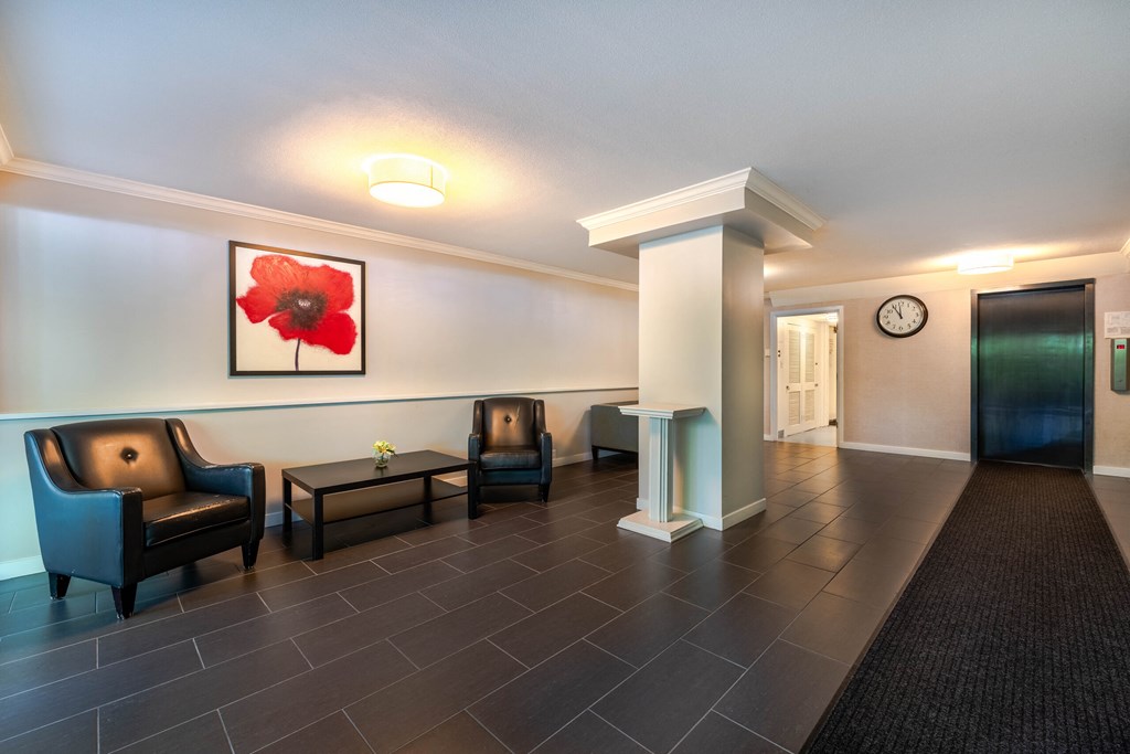 A hallway with a red flower on the wall and two chairs.