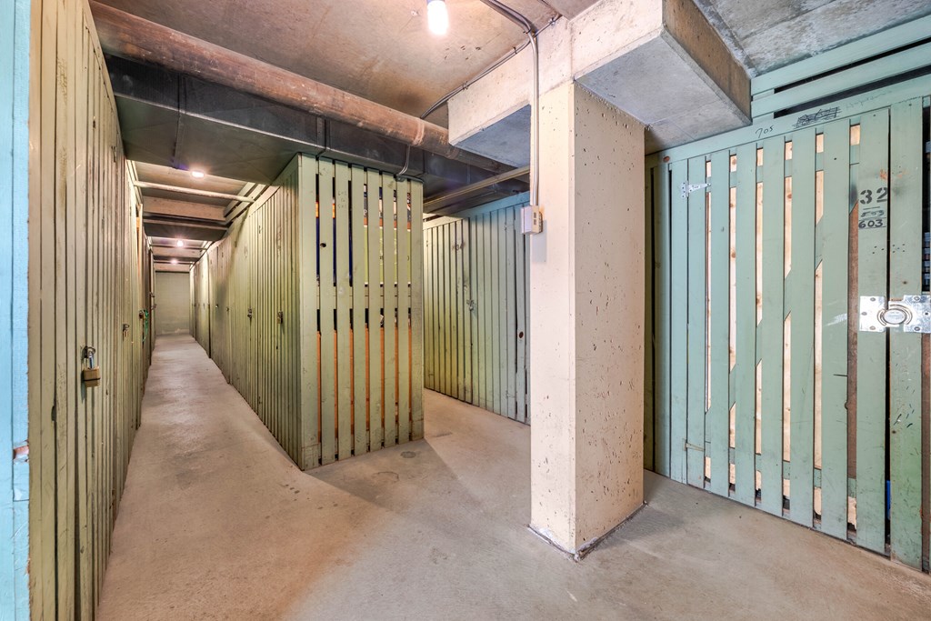 A long hallway with green doors and concrete pillars.