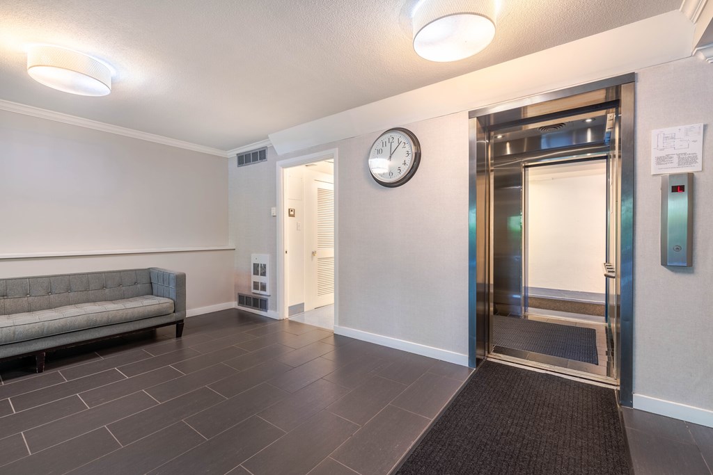 A hallway with a clock on the wall and a door on the right.