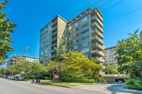 A modern apartment building with a parking lot in front.