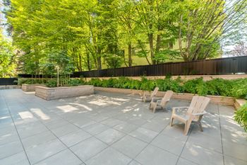 A patio with chairs and a table surrounded by a fence and trees.