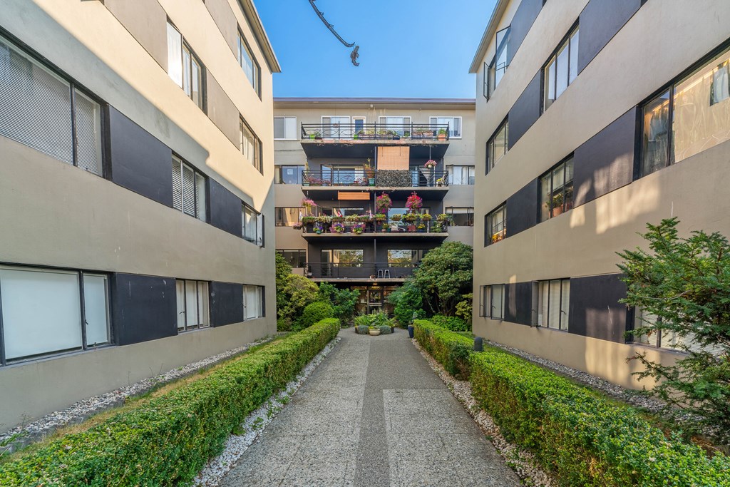 A long, narrow walkway separates two buildings with balconies.