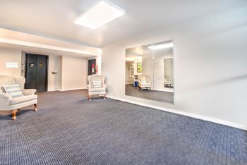 A spacious room with a blue carpet and a mirror on the wall.