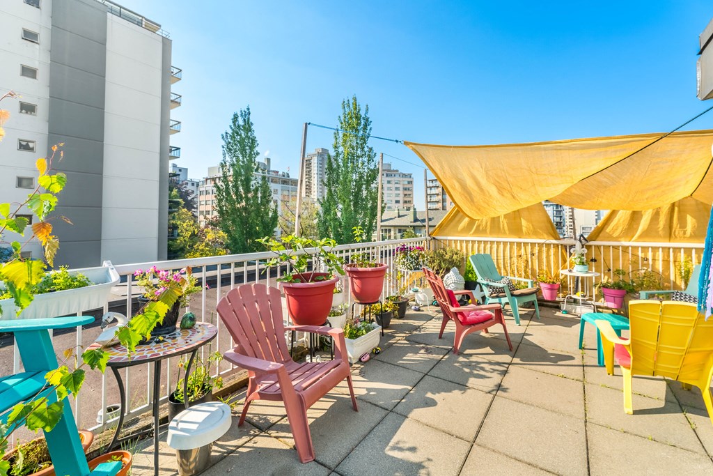 A patio with a table, chairs and a yellow canopy.