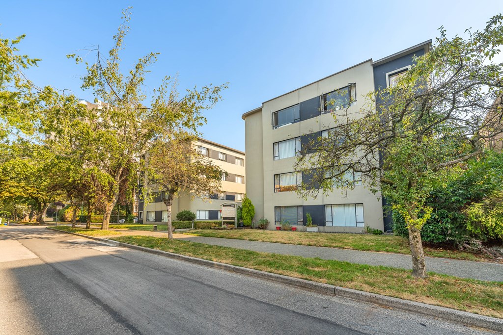 A street view of a residential area with apartment buildings and trees.