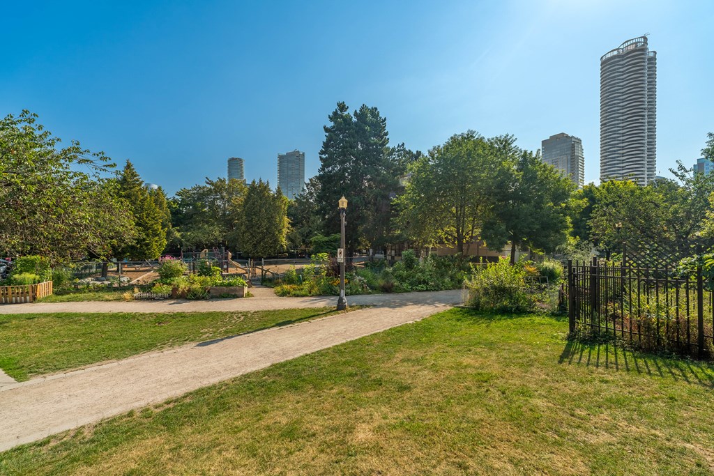 A park with a dirt path and a tall city skyline in the background.