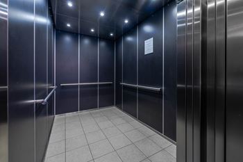 A stainless steel elevator with a white paper on the wall.