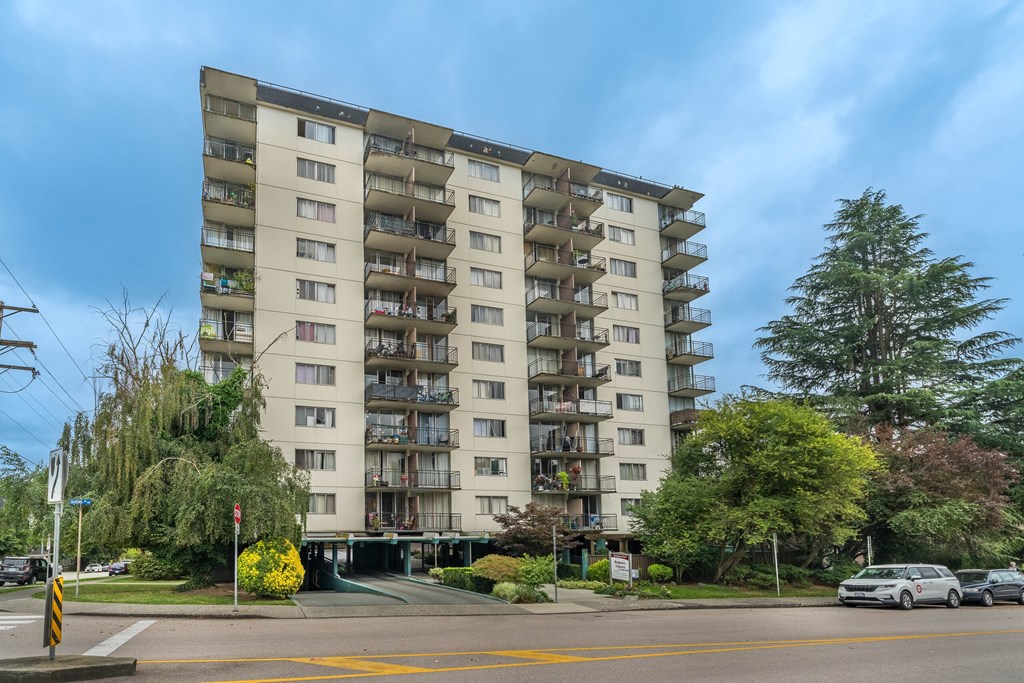 A large apartment building with balconies and a yellow crosswalk in front.