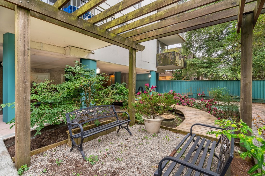 A wooden pergola over a bench in a garden.