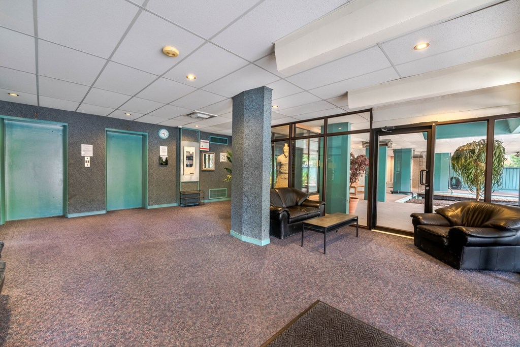 A room with a carpeted floor and a column in the middle.