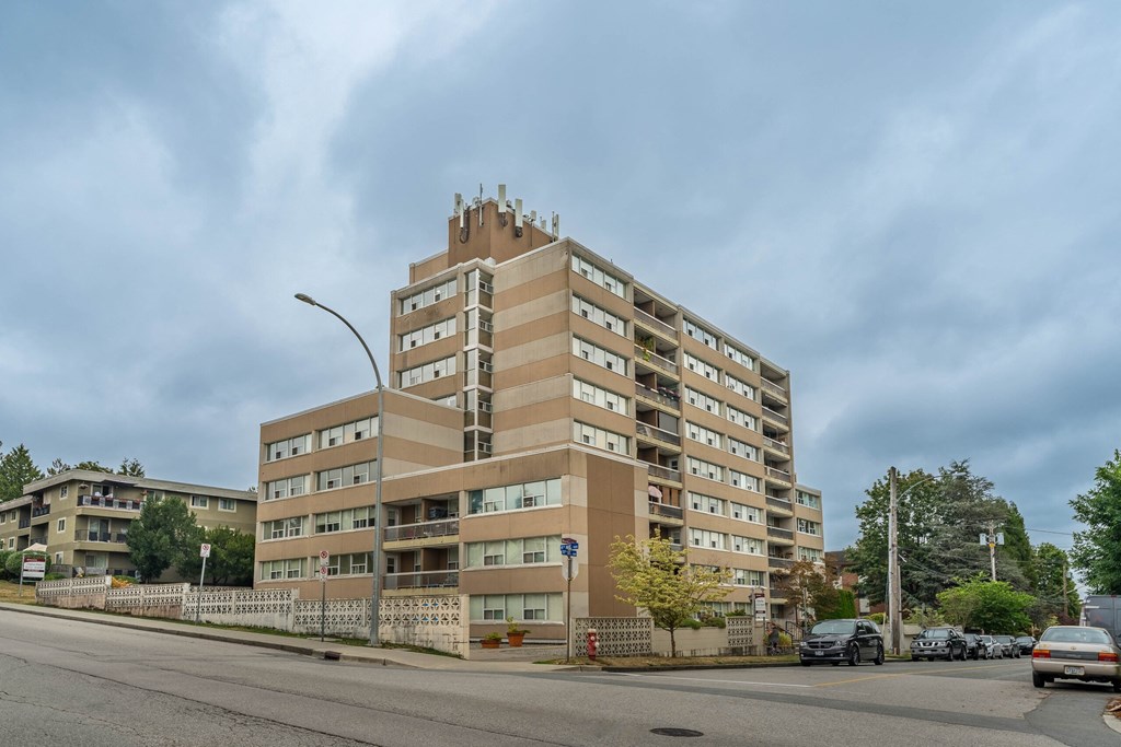 A large apartment building with a parking lot in front.