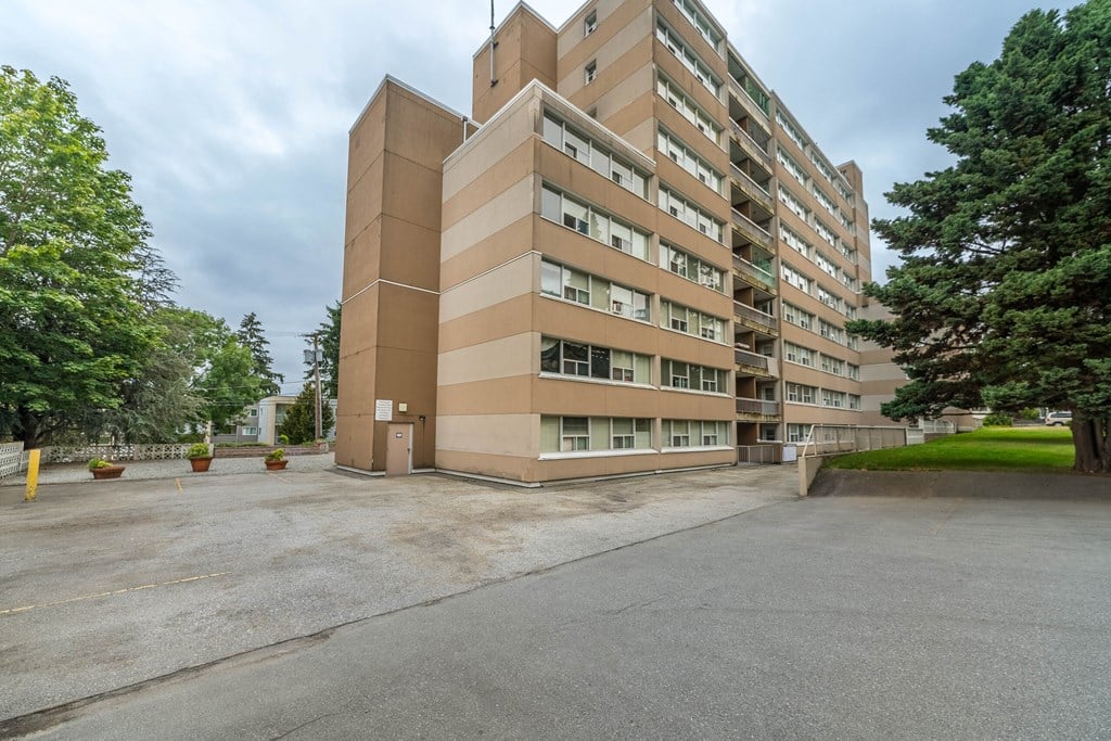 A large beige building with a parking lot in front.