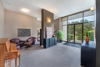 A living room with a brown leather couch and a wooden piano.