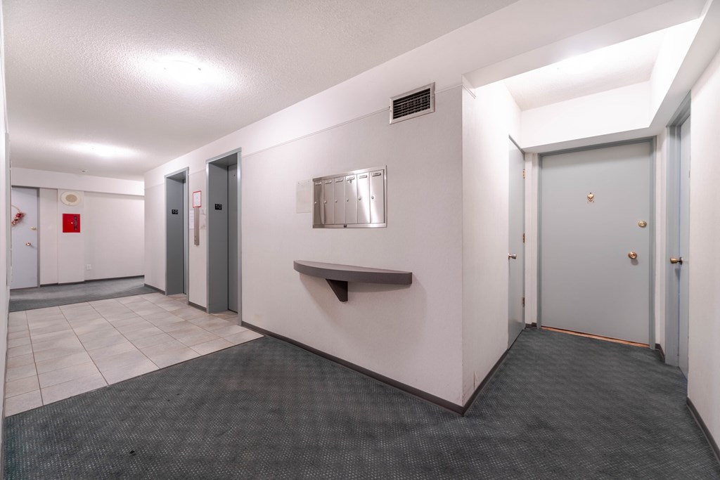 A hallway with a bench, doors, and a fire extinguisher.