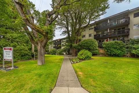 A well-maintained lawn with a sign for a condominium.