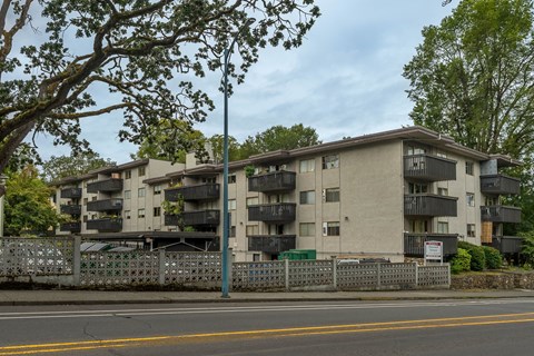 Apartment building with a fence and trees in front.
