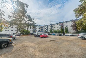 A parking lot with cars and trees in front of a building.