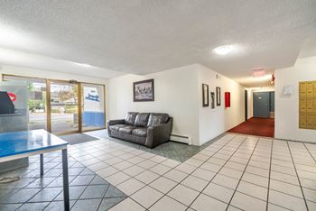A living room with a grey couch and a glass table.