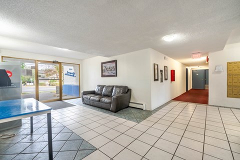 A living room with a grey couch and a glass table.