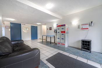 A living room with a black leather couch and a blue door.
