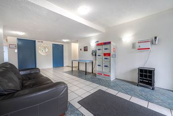 A living room with a black leather couch and a blue door.