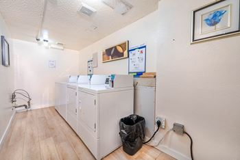 A kitchen with a fridge, a cupboard and a trash bag.