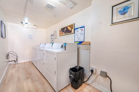 A kitchen with a fridge, a cupboard and a trash bag.