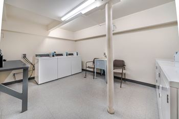 A room with a white cabinet, a chair, and a table.