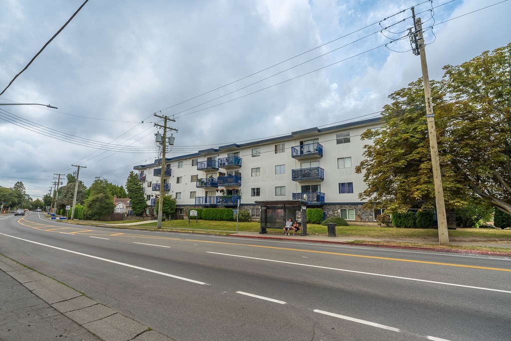 A street view with a building on the right and a tree on the left.