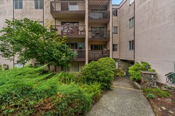 A concrete pathway leads to a building with a balcony.