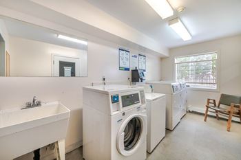 A laundry room with a washer and dryer, a sink, and a chair.