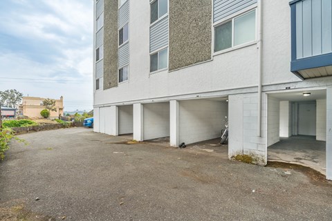 A parking lot in front of a white building with a blue car parked in the background.