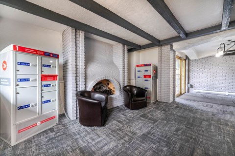 A room with a vaulted ceiling has a wall of lockers on the left and two leather chairs.