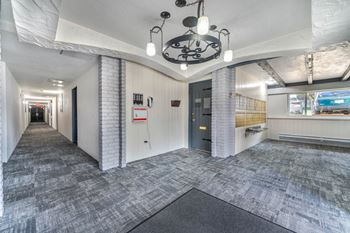 A long hallway with a brick wall and a black door.